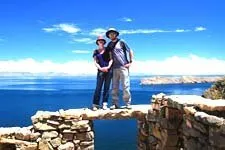 Una pareja sobre el muro de las ruinas de Pilcocaina, al fon