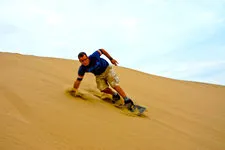 Young man sandboarding near Huacachina Oasis in Ica, Peru.