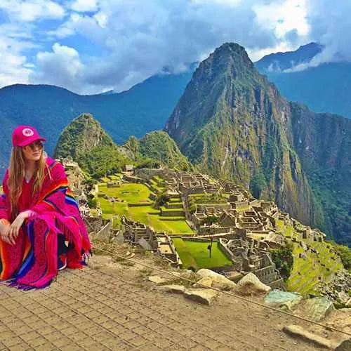 Mujer sentada con fondo de Machu Picchu